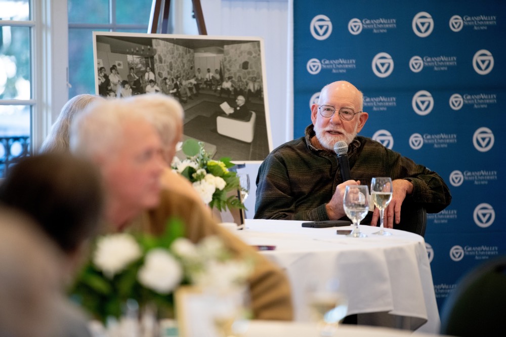Man sitting down at table hold microphone while he talks